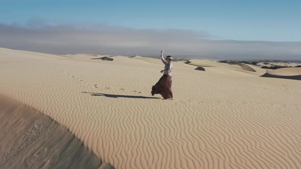 Woman in Virtual Reality Headset Controllers Drawing or Painting on Sand Dunes alt