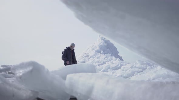 The Lonely Male Tourist on the Background Walking on the Glacier