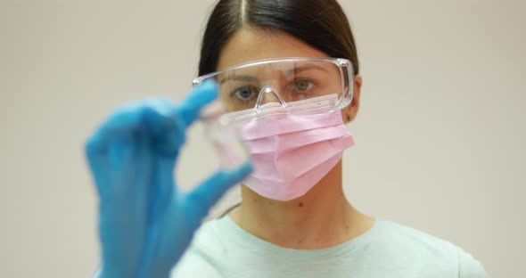 Doctor scientist with protective gloves and face mask holding vaccine medicine dose stock photo