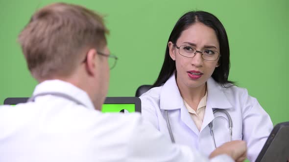 Young Asian Woman Doctor Having Meeting with Young Man Doctor