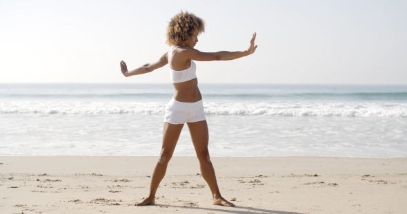 Woman Practices Yoga On A Beach