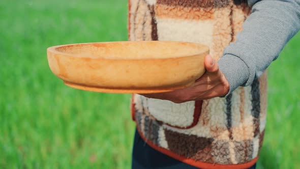 A Young Peasant Man Is Sowing the Field with Grain at a Village. A Farm Concept.