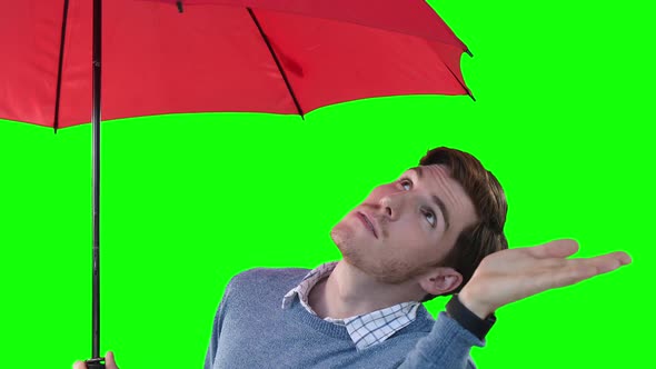 Caucasian man with an umbrella raising hand on green background