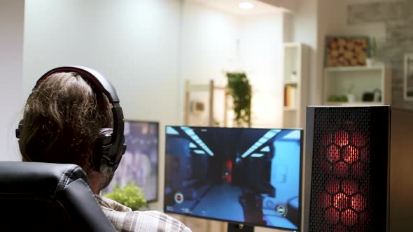 Over Shoulder Shot of Man with Long Hair Playing Shooter Games