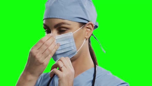 Caucasian female doctor wearing face mask on green screen background