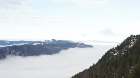 Aerial jib down of low hanging clouds in beautiful mountain valley