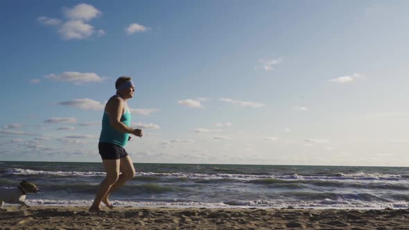 Fat Man Overweight Doing Jogging Exercises On Sandy Sea Shore