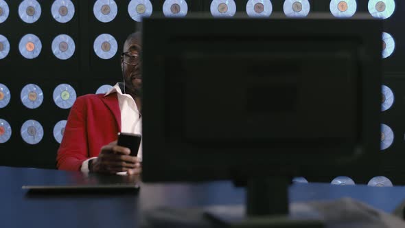 Black Bald Bearded Cute Businessman in Red Suit and Glasses Speaks on Phone