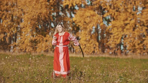 Woman in Red National Dress Standing on the Field and Fencing with a Sword - Throws It Up