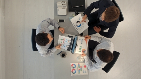 Creative Team Displaying Charts  With Laptop And