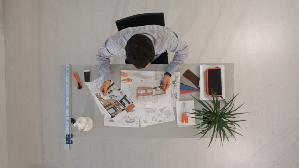 Engineer With Blueprints Of Object And Laptop. Top alt