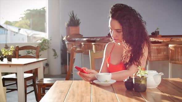 Young Girl or Woman Drinking Coffee in Cafe Texting Sharing Messages on Social Media Enjoying Mobile