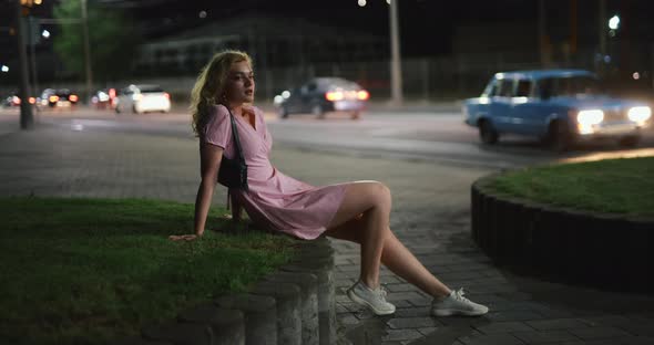 Beautiful Woman Sitting at Night City Street