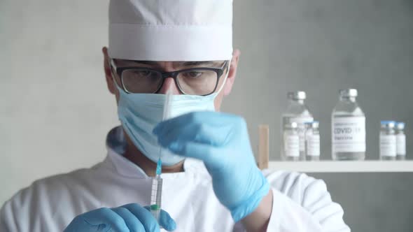 GP Wearing Medical Face Mask Looking Onto a Syringe with Needle