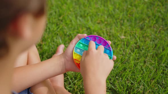 Closeup of a Child Hands Playing with a Popit on Green Nature Background