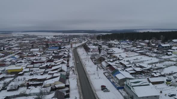 White passenger car rides on the road in winter village. Aerial