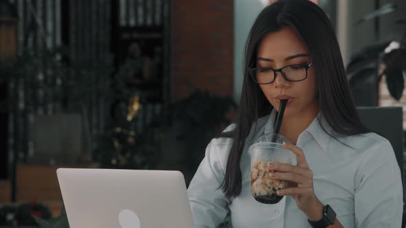 Asian Attractive Young Woman Wearing Glasses Working at Her Laptop on the Street