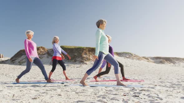 Athletic women performing yoga in the beach