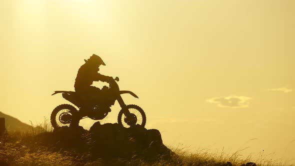Silhouette of Extreme Pro Motocross Biker Riding Motor Bike Opposite Sunrise