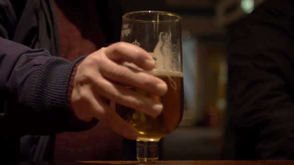 Man's hand with glass of beer in a bar close up shot
