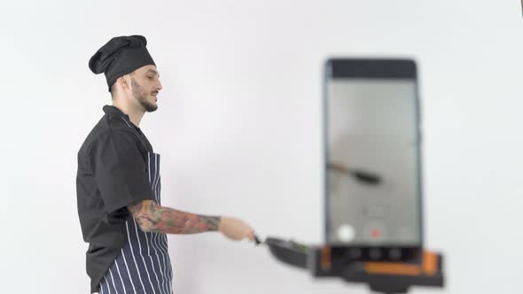 Professional Male Chef Tossing Vegetables in Wok During Online Lesson