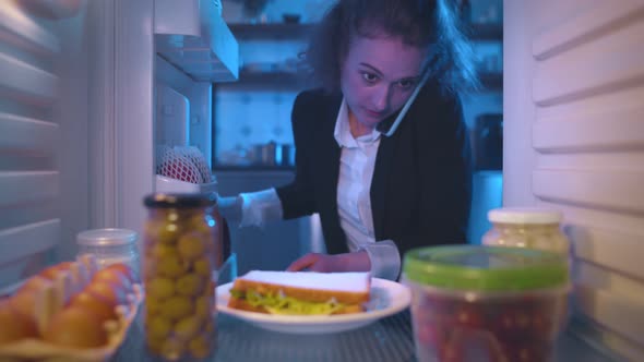 Businesswoman Looking For Food Inside Fridge In Kitchen