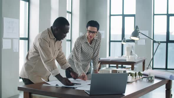 Diverse Male and Female Architects Discussing Construction Plan