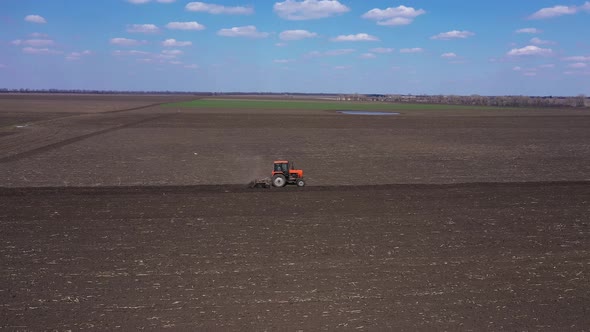 Farm Red Tractor Plows the Field and Prepares for Sowing Aerial View