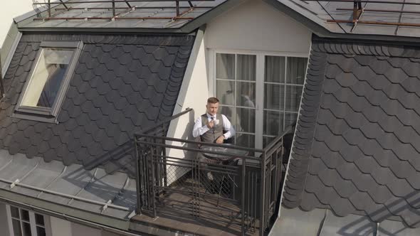 Man Groom Businessman Is Drinking Coffee From a White Cup on the Balcony at Home in Wedding Morning