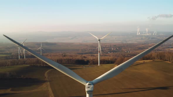 Close Up a Large Spinning Wind Turbine on the Background of Wind Farm at Sunset