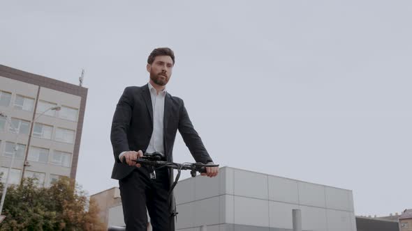 Young Modern Business Man in a Suit Riding an Electric Scooter