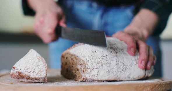 Closeup Hands of Woman Cutting a Bread on a Wooden Floor in a Kitchen