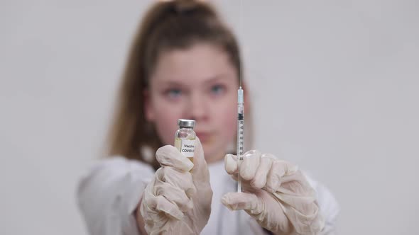 Closeup Covid Vaccine Jab and Syringe in Little Female Hands with Blurred Caucasian Girl Sprinkling