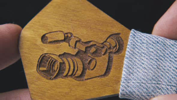 Man Shows Wooden Bow Tie with Camera on Dark Background