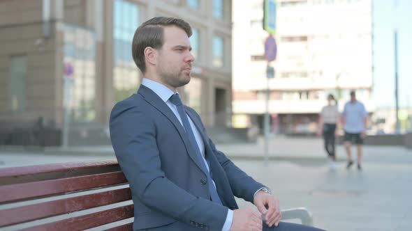 Businessman Looking at Camera while Sitting on Bench