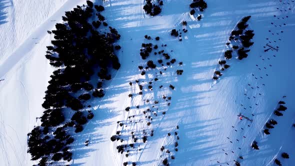 Aerial view of the ski lift at the foot of the ski slope with a crowd of skiers and snowboarders. Al