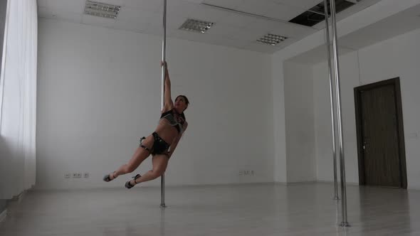 Seductive Female Doing Pole Dance in Studio