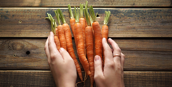 Placing A Bunch Of Baby Carrots On Wooden Table