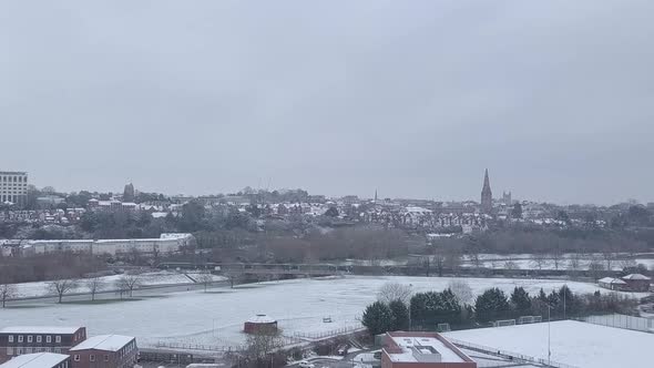 High dolly forward drone shot of a snowy Exeter as a train passes by CROP