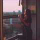 Woman photographer taking a picture from the balcony during golden hour - VideoHive Item for Sale