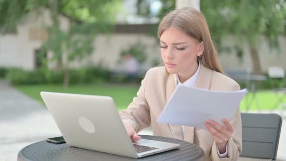 Young Businesswoman with Laptop Having Loss While Reading Documents