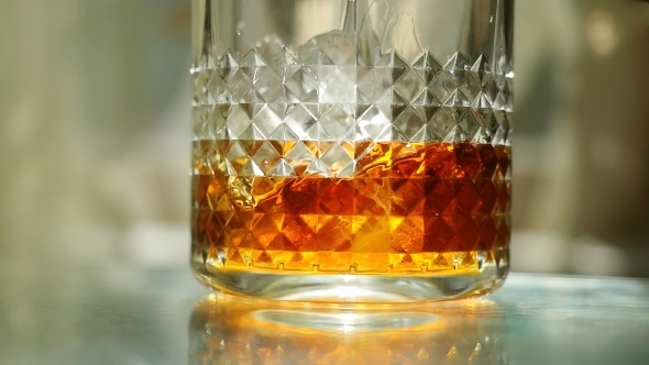 Throwing Ice Cubes In a Glass Of Whiskey