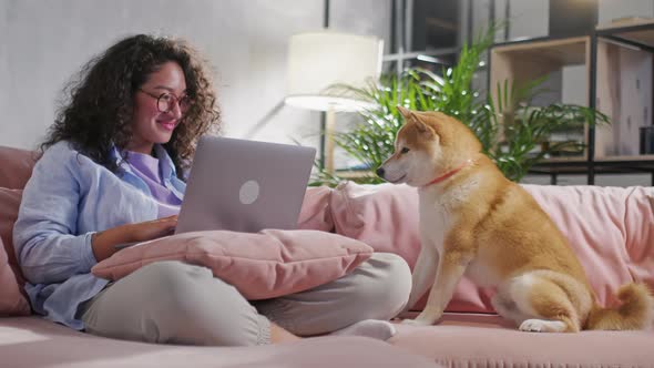 Young Brunette Woman in Casual Clothes While She Works with a Laptop in Sofa