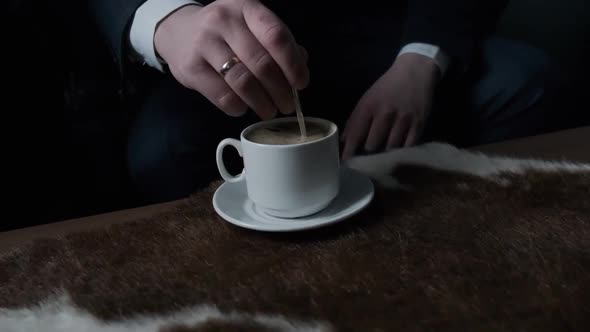 Man's Hand Stirs a Cup of Coffee