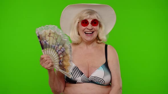 Elderly Woman Tourist in Swimsuit Bra Exhales From Heat or Stuffiness Waves Hand Fan at Herself