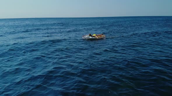 Woman in Yellow Closed Bathing Suit Floats on the Sea or Ocean on Yellow Inflatable Mattress in the