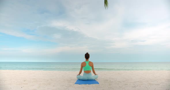 Woman Meditating in the Morning She Seats on the Beach After Exercise and Enjoys the View