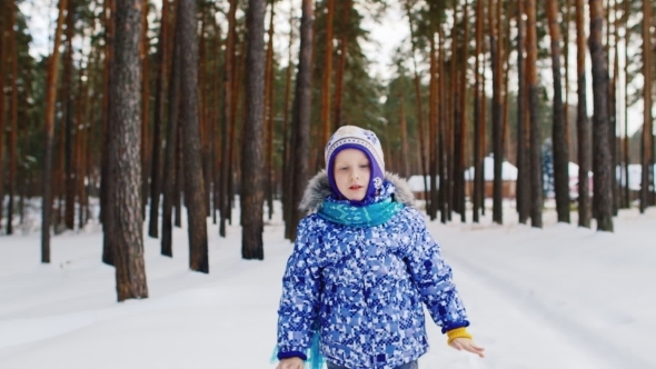 The Little Girl Laughs And Goes On Snow-covered Road