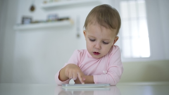 Young Child Plays On A Modern Smartphone In The Interior