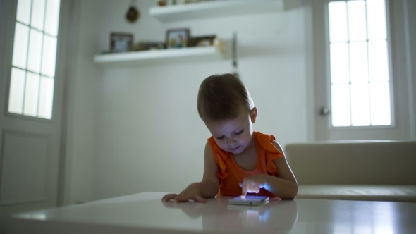 Young Child Plays On A Modern Smartphone In The Interior
